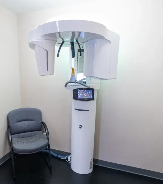Cone beam CT scanner in dental treatment room with patient chair.