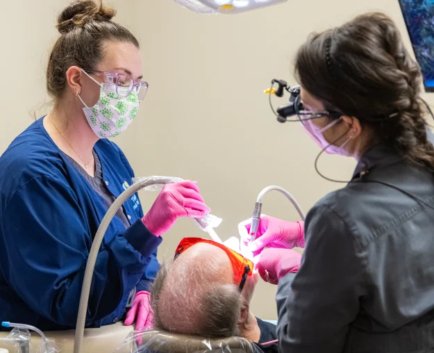 Dentist and assistant performing a laser dental procedure on a patient
