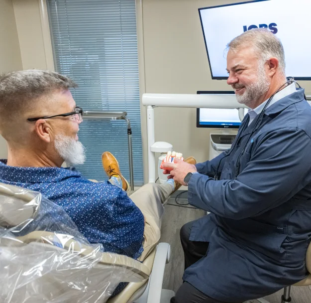 Dentist showing a patient a tooth model during a consultation at W. Eric Martin, DDS, PC