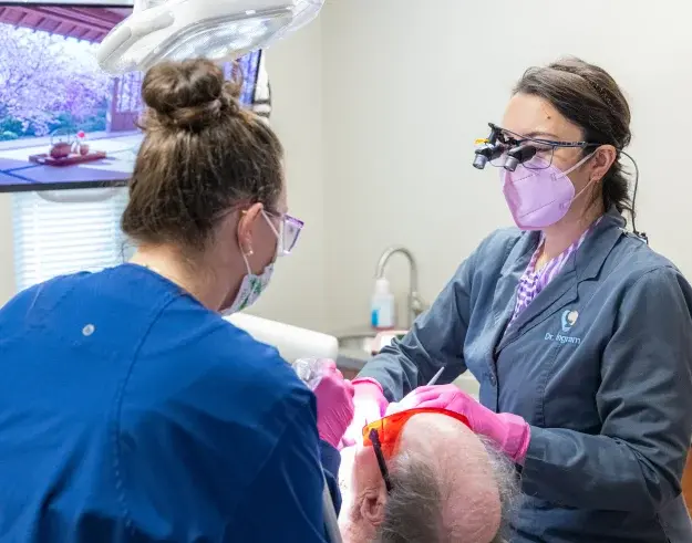 Dental hygienist performing professional teeth whitening treatment on patient in Champaign clinic